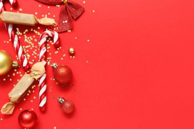 Kırmızı arka planda süslemeler, şekerler ve konfetilerle güzel bir Noel kompozisyonu