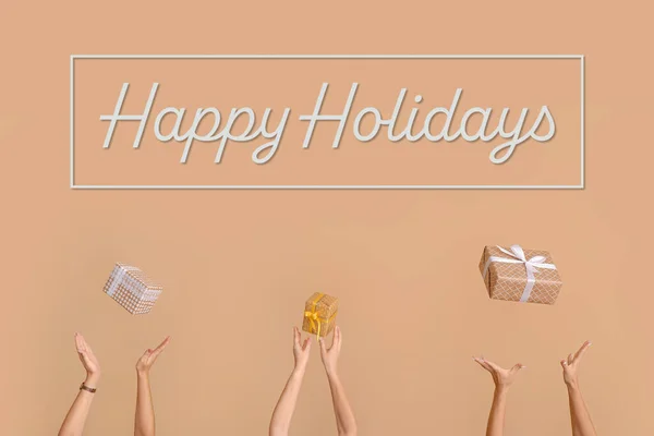 Hands with gift boxes on beige background. Happy holidays