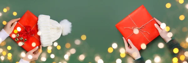 Banner with Christmas gifts in hands on green background
