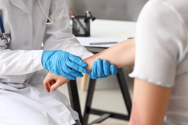 診療所で傷を負った患者の腕を調べる女性医師 — ストック写真