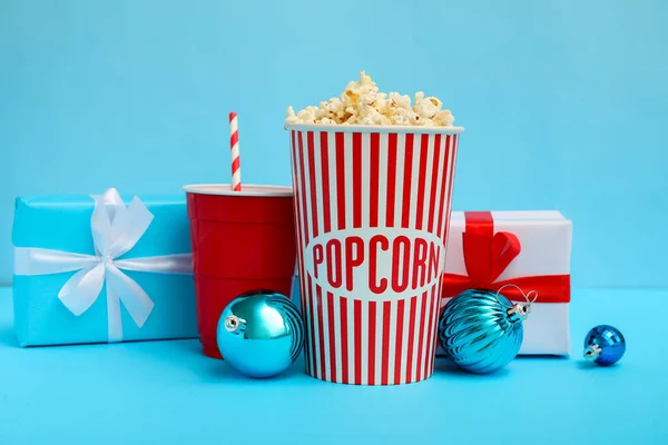 stock image Bucket of popcorn, cup, presents and Christmas balls on blue background