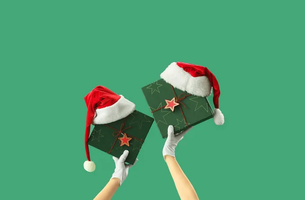 Frau Mit Weihnachtsgeschenkschachteln Und Weihnachtsmützen Auf Grünem Hintergrund — Stockfoto