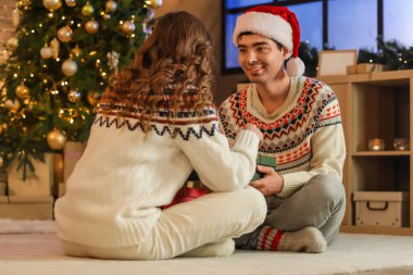 Genç aşık çift Noel arifesinde evde hediyelerini açıyor.