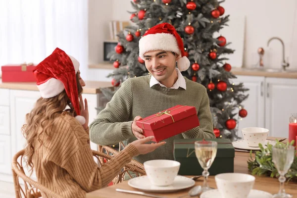 Fiatal Férfi Köszönti Szeretett Feleségét Ajándékkal Konyhában Karácsony Este — Stock Fotó
