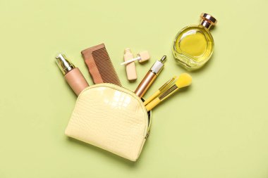 Yeşil arka planda aksesuarları olan sarı kozmetik çanta