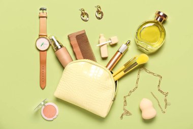 Yeşil arka planda kozmetik ve aksesuarlı sarı çanta