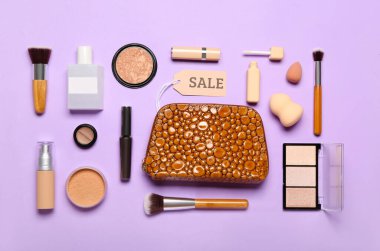 Kozmetik ürünleri, aksesuarlar ve eflatun arka planda satış etiketi olan çanta