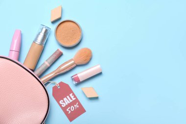 Kozmetik ürünleri, aksesuarlar ve mavi arka planda satış etiketi olan çanta