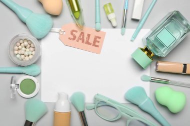 Kozmetik ürünleri, aksesuarlar ve gri arka planda satış etiketi olan boş kağıt kağıtlar.