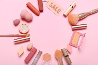 Pembe arka planda kozmetik, fırça, sünger ve satış etiketlerinden yapılmış çerçeve
