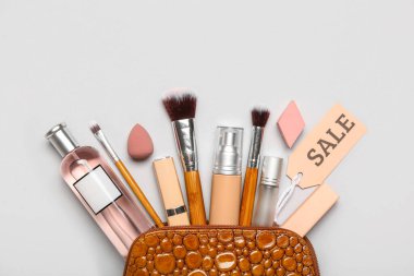 Gri arka planda kozmetik ürünleri ve satış etiketi olan çanta