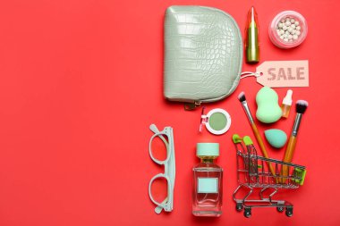 Kırmızı arka planda kozmetik, aksesuar ve satış etiketi olan çanta