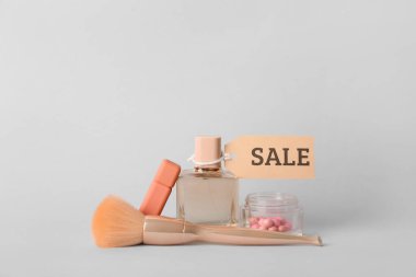 Makyaj fırçası, bir kavanoz toz inci, parfüm, ruj ve açık arkaplanda satış etiketi