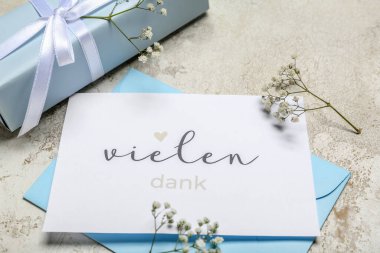 Grunge arka planında metin VieLEN DANK, zarf, çiçekler ve hediye kutusu olan kart