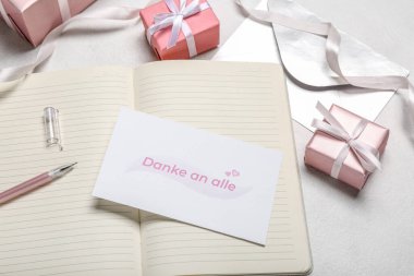 Açık arkaplanda DANKE A ALLE, dizüstü bilgisayar, kalem ve hediye kutuları olan kart, kapat