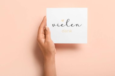 Renk arkaplanında VİELEN DANK yazılı kartı olan kadın, kapat