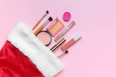 Pembe arka planda makyaj ürünleri olan Noel çorabı