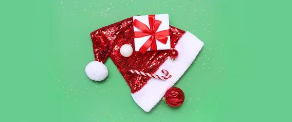 緑の背景にクリスマスの装飾 サンタの帽子と贈り物と構成 — ストック写真
