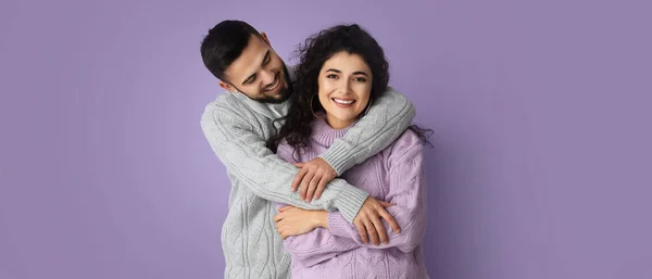 幸せな若いですカップルで暖かいですセーター上のLilac背景 — ストック写真