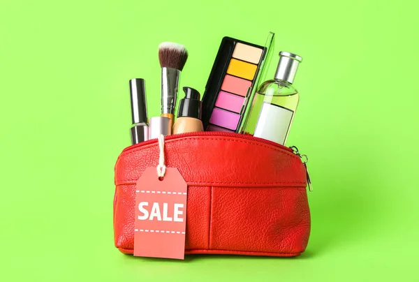 緑の背景に化粧品製品や販売タグ付きレッドバッグ — ストック写真