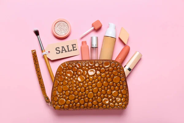 Bag with cosmetics, brush and sale tag on pink background