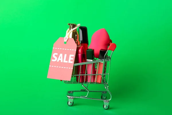 緑の背景に化粧品 スポンジと販売タグ付きショッピングカート — ストック写真