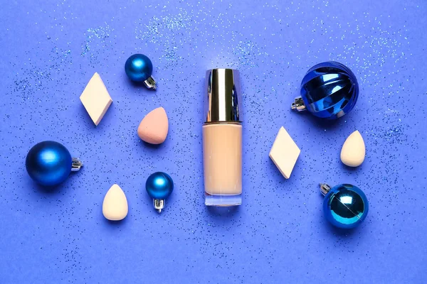 Süngerli makyaj vakfı ve mavi arka planda Noel topları