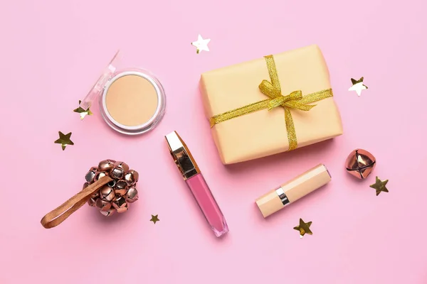 ピンクの背景にクリスマスの鐘や贈り物と化粧品 — ストック写真