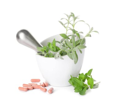 Farklı otlar ve beyaz arka planda haplarla havan topu.