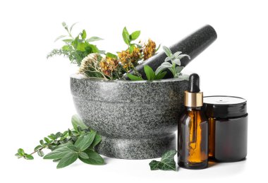 Farklı otlar ve beyaz arka planda gerekli yağ içeren taş havan taşı.