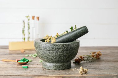 Tahta masada bitkiler ve haplarla taş havan topu.