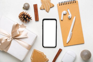 Cep telefonu, kulaklık, Noel hediyesi ve arka planda not defteri olan kompozisyon