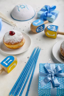 Beyaz arka planda Hanuka kutlaması için donut, dreidel, mum ve hediyelerle dolu bir tabak.