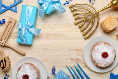 Donut, menorah, dreidel ve hediyelerden oluşan çerçeve tahta arka planda Hanuka kutlaması için.