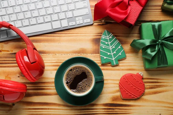Cup of coffee, Christmas gifts, cookies, headphones and keyboard on wooden background