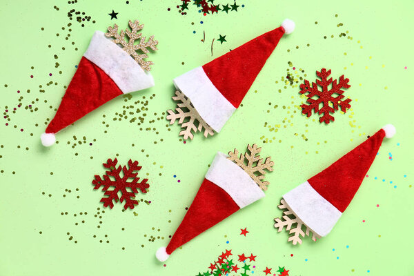 Composition with Santa hats, Christmas decorations and confetti on color background