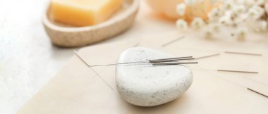 Akupunktur iğneleri ve masadaki spa taşı