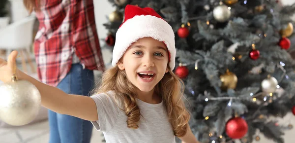 自宅でクリスマスツリーを飾る幸せな小さな女の子 — ストック写真