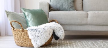 Yatak odasındaki kanepenin yanında yastık ve ekoseli sepet.