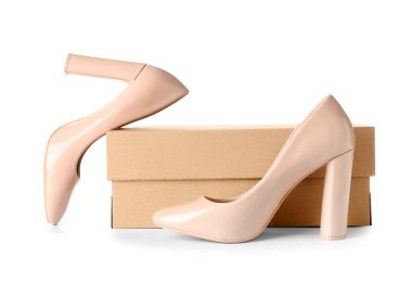 Beyaz zemin üzerinde yüksek topuklu bej ayakkabılar olan karton kutu.