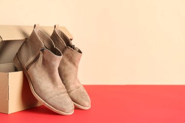 Bej duvarın yanındaki masada bej çizmeli karton kutu.