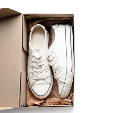 Beyaz arka planda spor ayakkabıları olan karton kutu