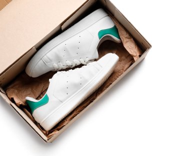 Beyaz arka planda spor ayakkabıları olan karton kutu