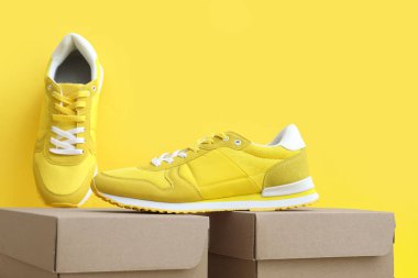 Sarı arka planda spor ayakkabıları olan karton kutular.