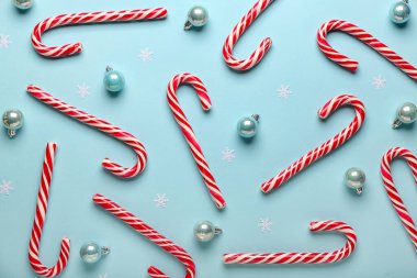 Mavi arka planda Noel topları olan şeker kamışları