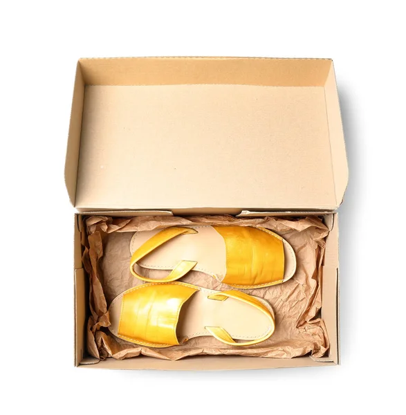 stock image Cardboard box with yellow sandals on white background