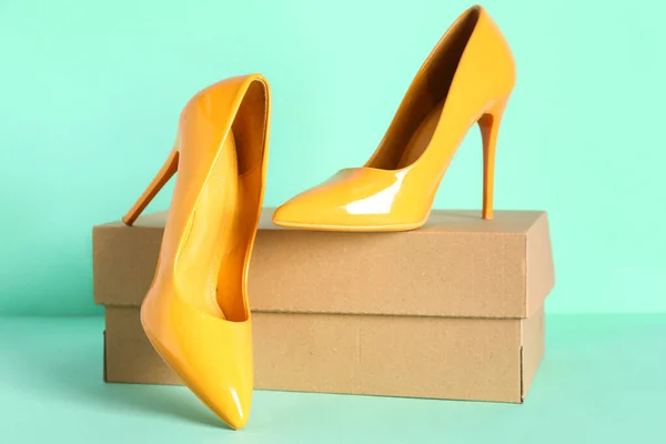 背景色に黄色のハイヒールの靴を持つ段ボール箱 — ストック写真