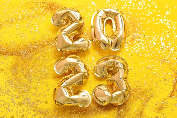 Figure 2023 made of balloons with glitter on yellow background