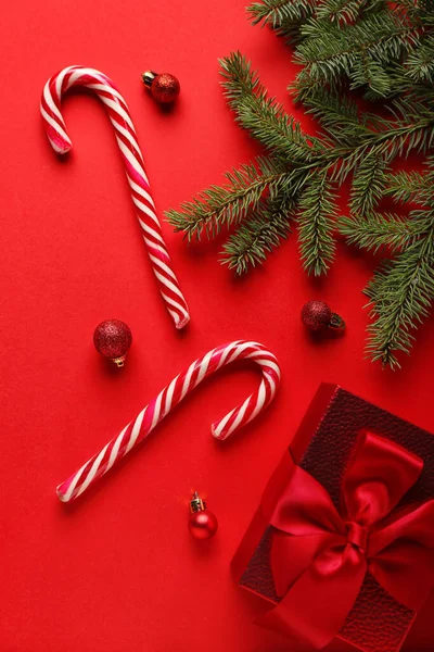 Zuckerstangen Mit Weihnachtskugeln Geschenk Und Tannenzweigen Auf Rotem Hintergrund — Stockfoto