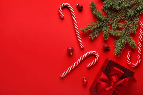 赤い背景にクリスマスボール ギフトやモミの枝を持つキャンディーの杖 — ストック写真
